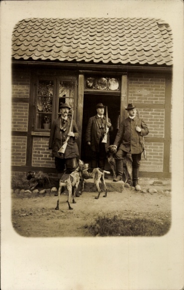 Foto Ak Jäger mit Gewehren und Hunden am Backsteinhaus